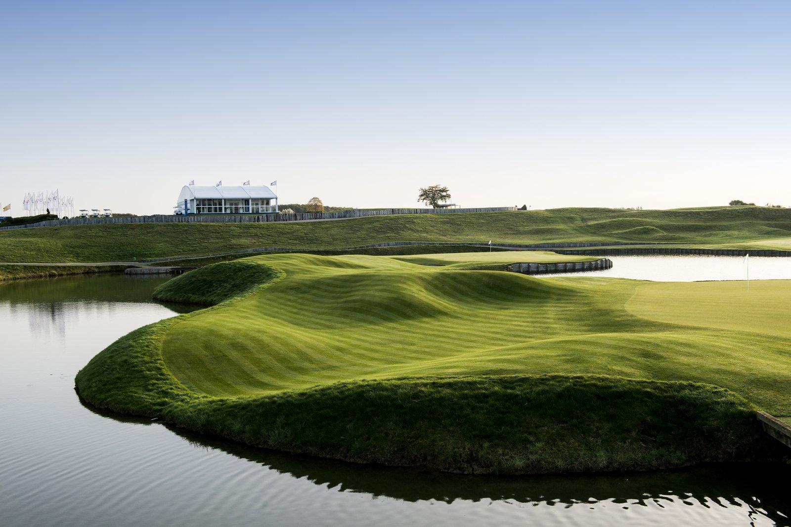 A well maintained fairway surrounded by a water hazard
