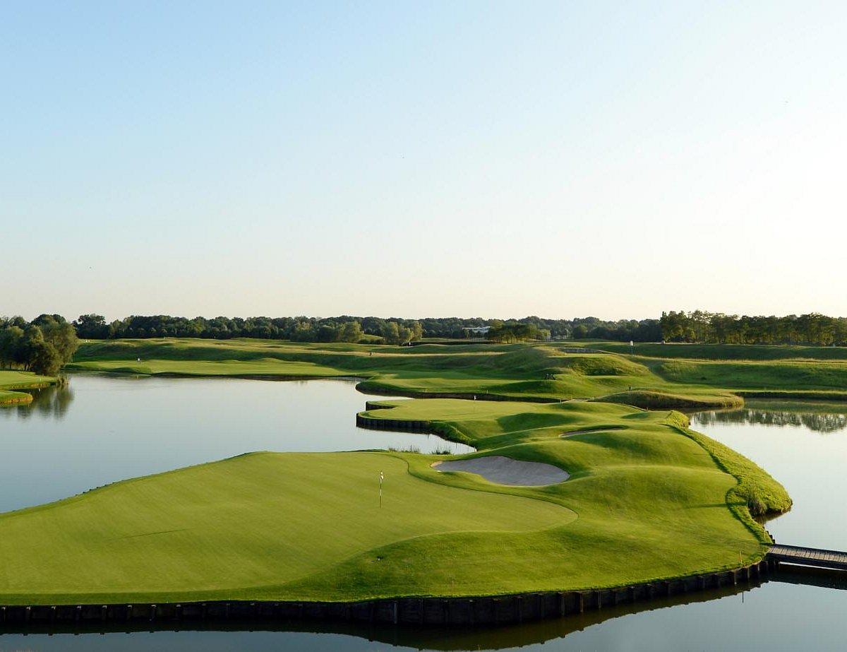 A well maintained fairway nestled with sand bunkers leading to a smooth green