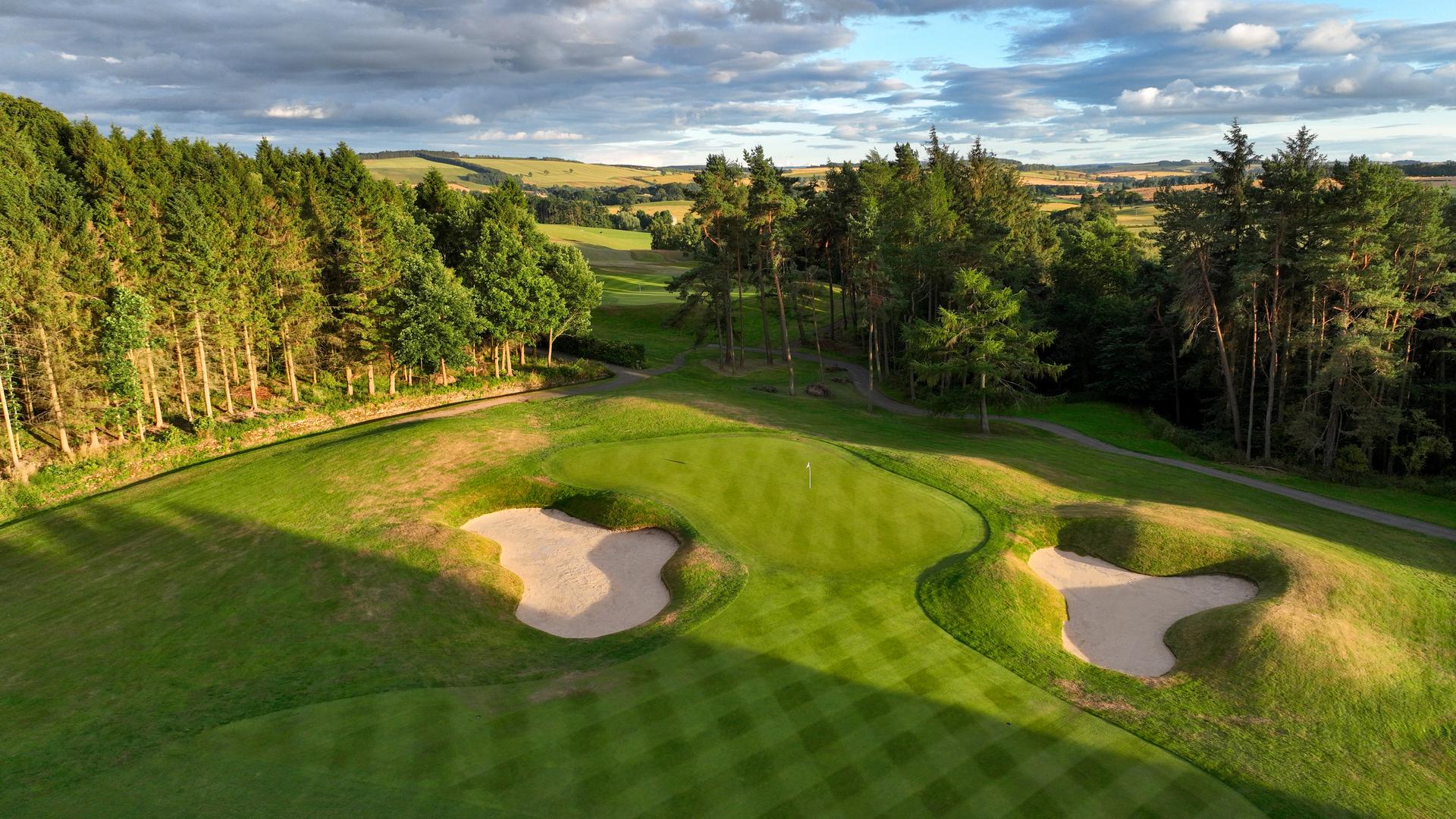 A well maintained fairway leading to a smooth green surrounded by sand bunkers at SCHLOSS Roxburghe