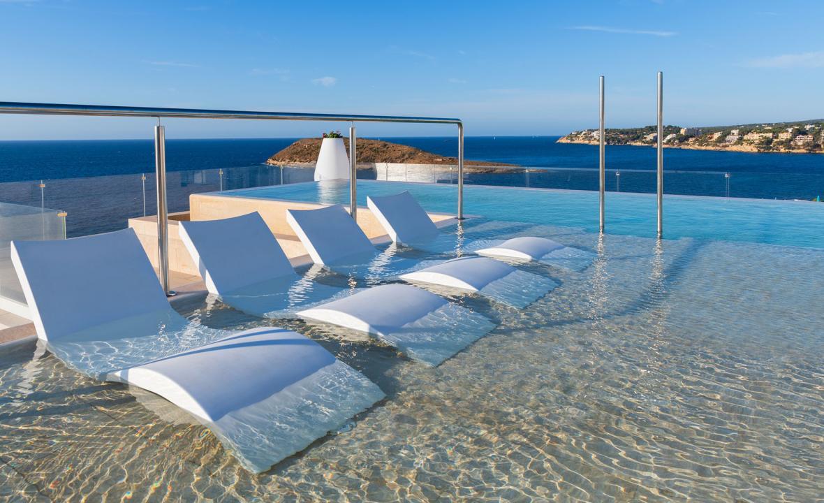 Outdoor pool with sunbeds and coastal views