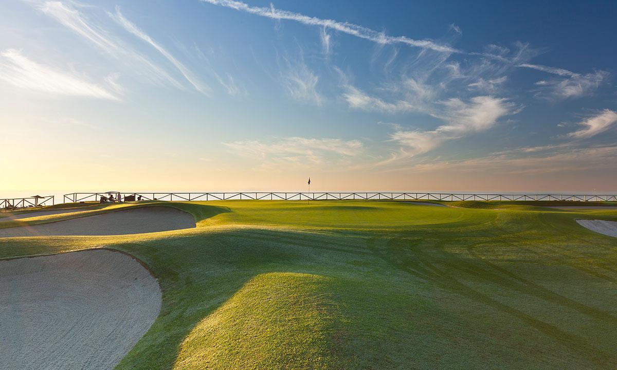 A coastal green under the sunset