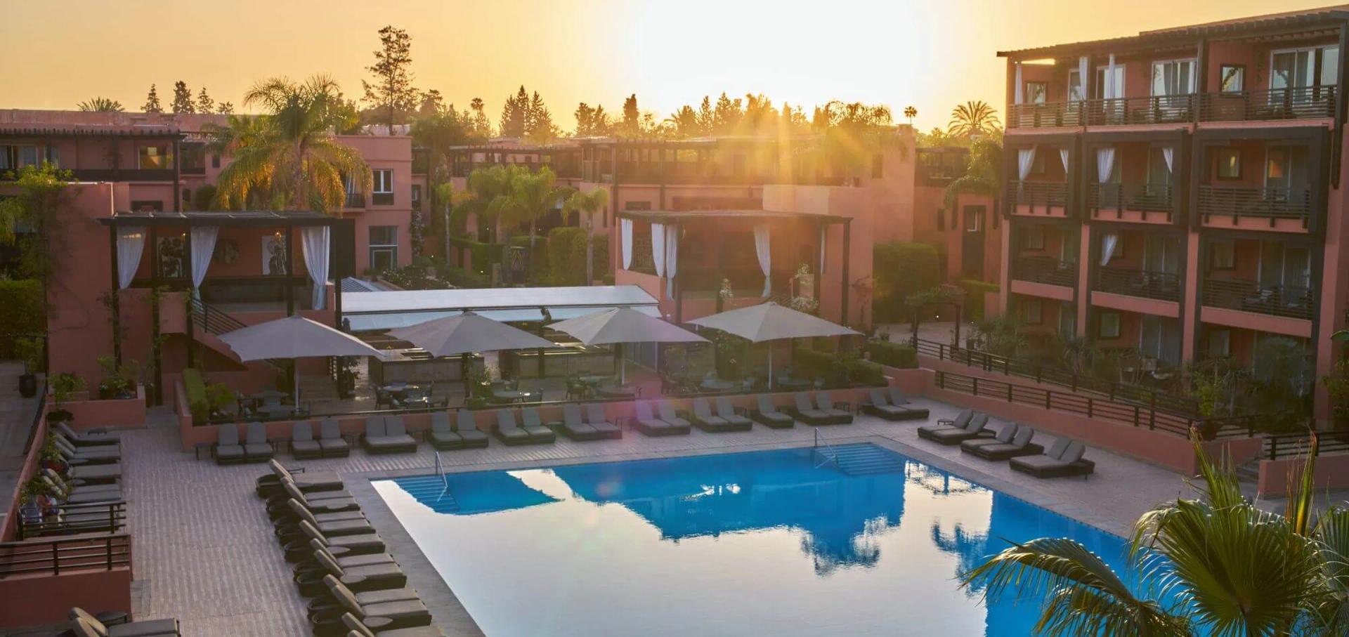 Overhead view of the sun setting over the outdoor pool at Hotel & Ryads Barrière Le Naoura
