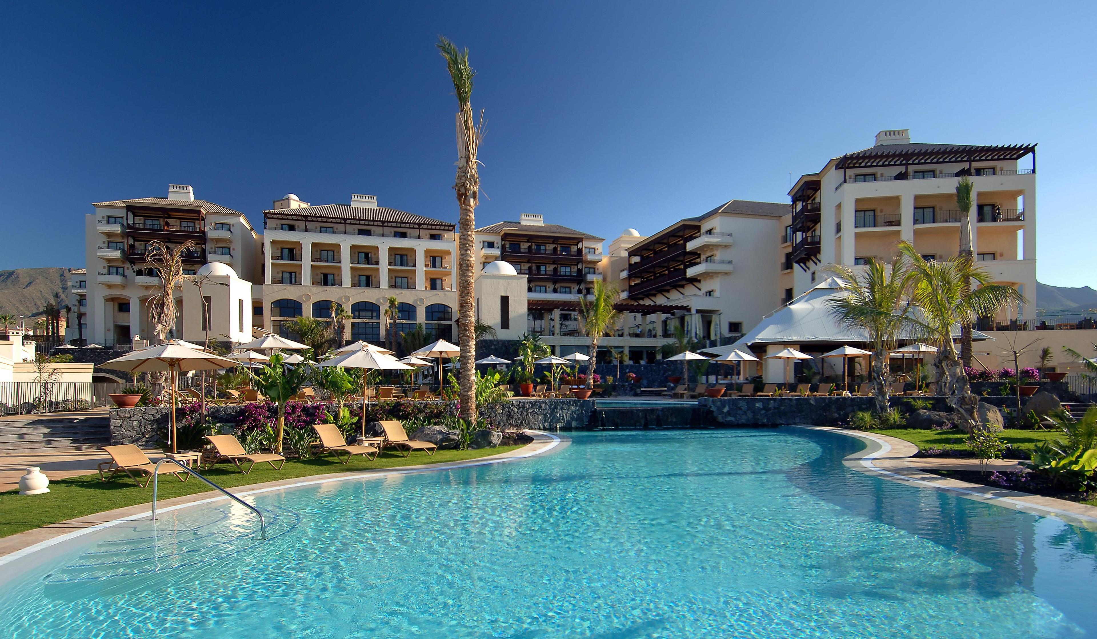 Panoramic view of the Hotel Vincci Seleccion La Plantacion del Sur building overlooking the outdoor swimming pool under clear blue skies