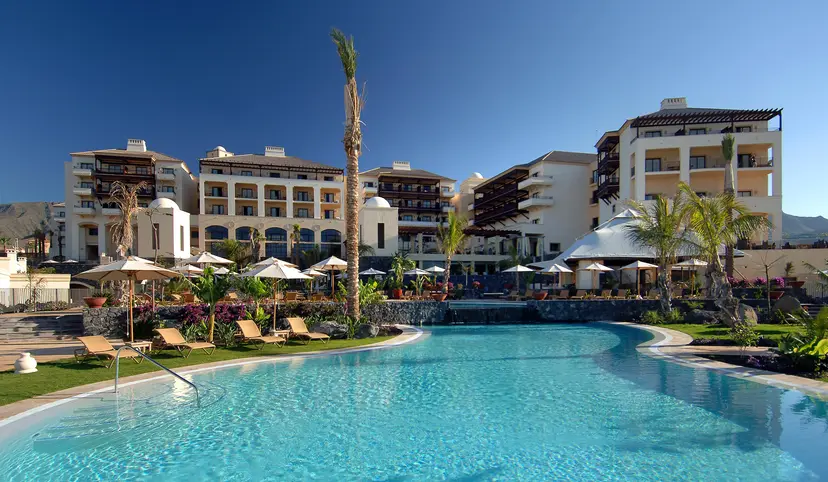 Panoramic view of the Hotel Vincci Seleccion La Plantacion del Sur building overlooking the outdoor swimming pool under clear blue skies