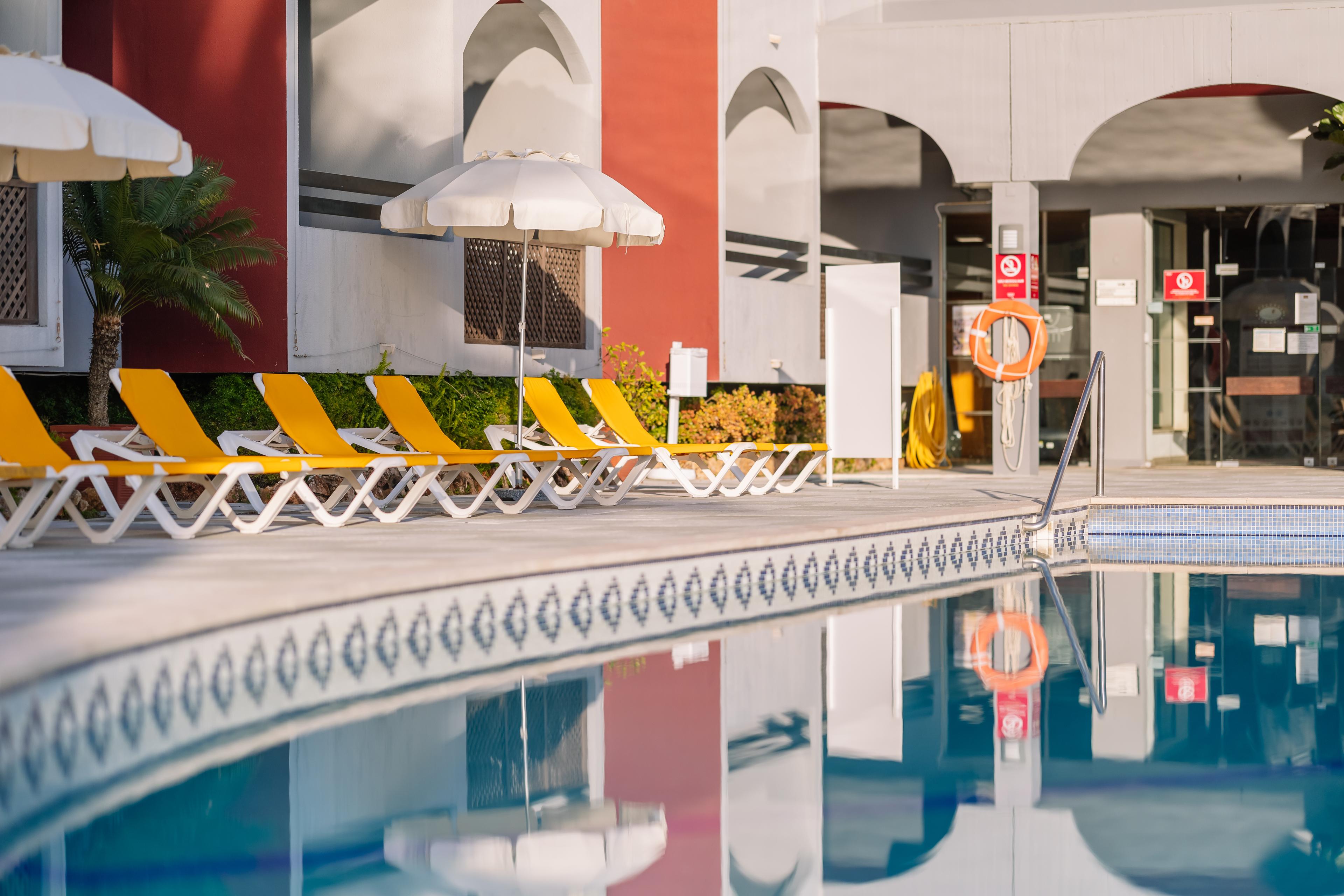 Outdoor pool lined with sunbeds at Muthu Oura Praia Hotel
