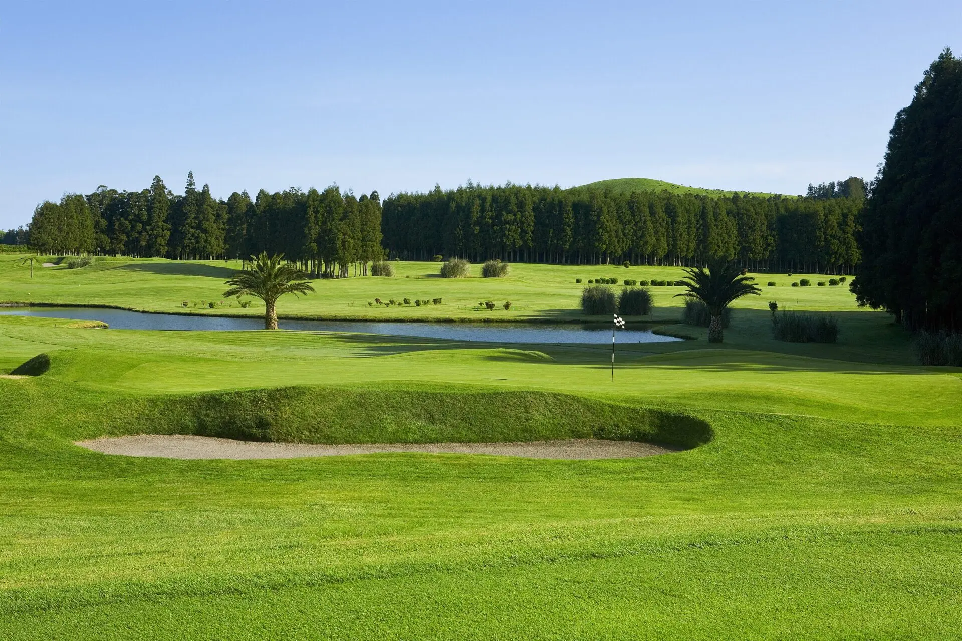 A deep sand bunker next to a manicured green at Octant Hotels Furnas