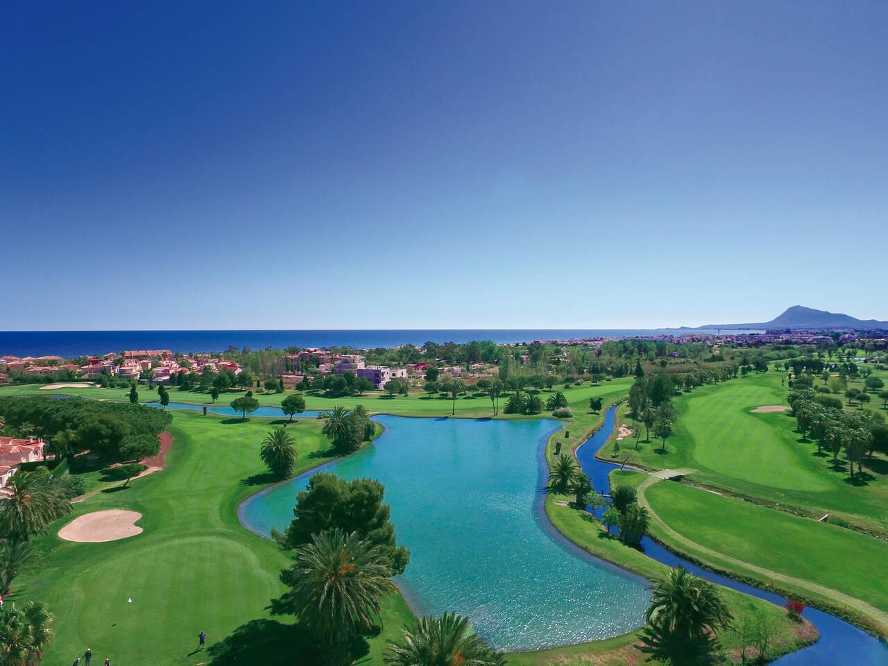 Overhead view of a well maintained fairway nestled with sand bunkers leading to a smooth green next to a water hazard