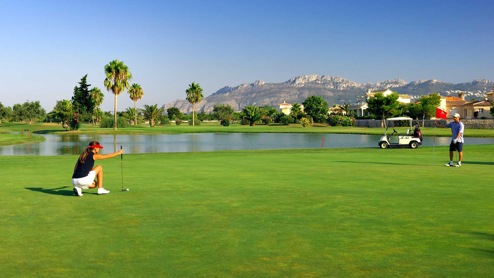 Golfer on a well maintained fairway next to a water hazard