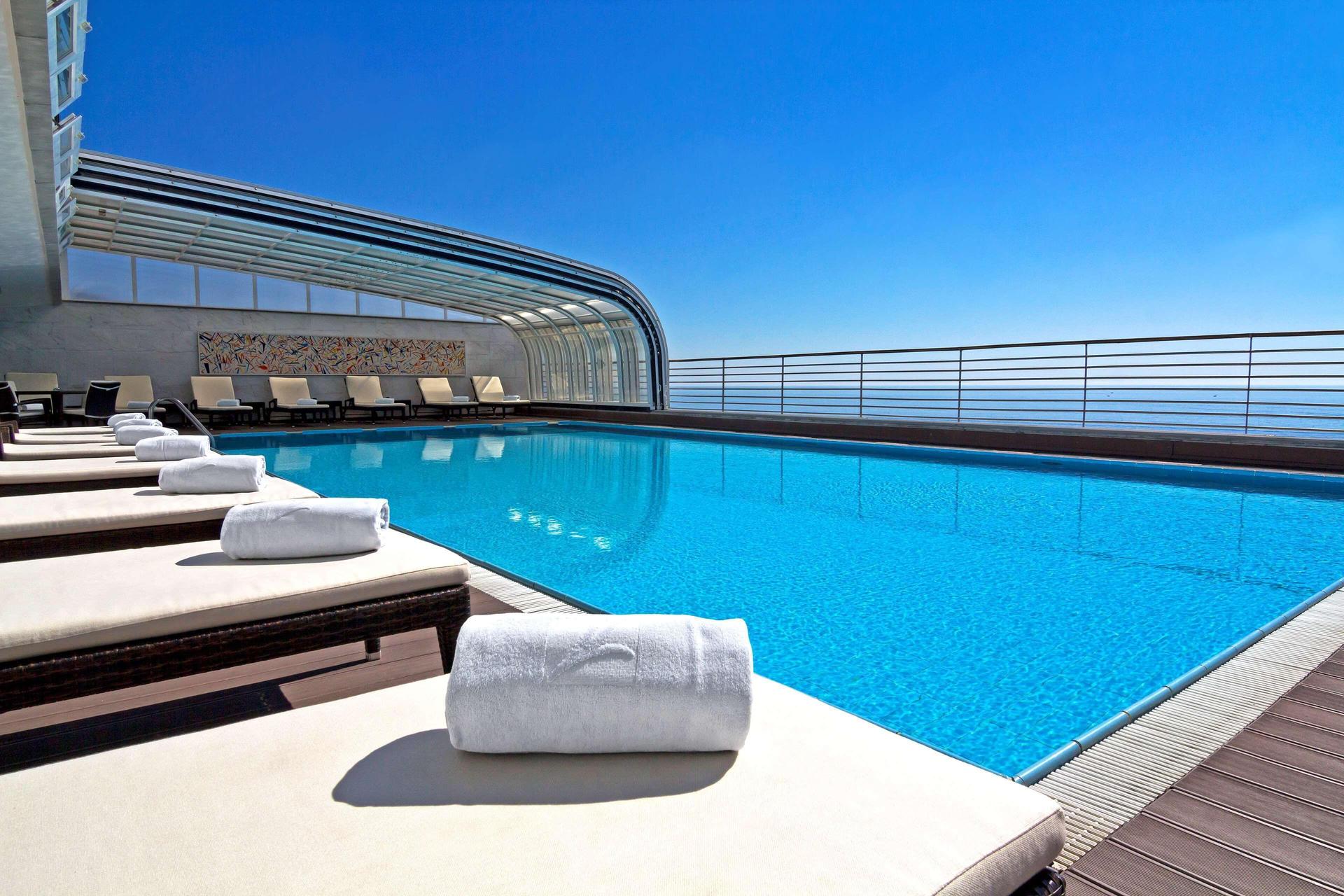 Rooftop pool under clear blue skies at SANA Sesimbra Hotel