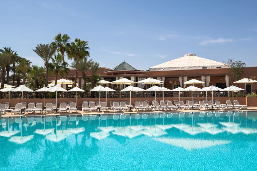 Outdoor swimming pool lined with sunbeds and umbrellas at Sol Oasis Marrakech by Melia