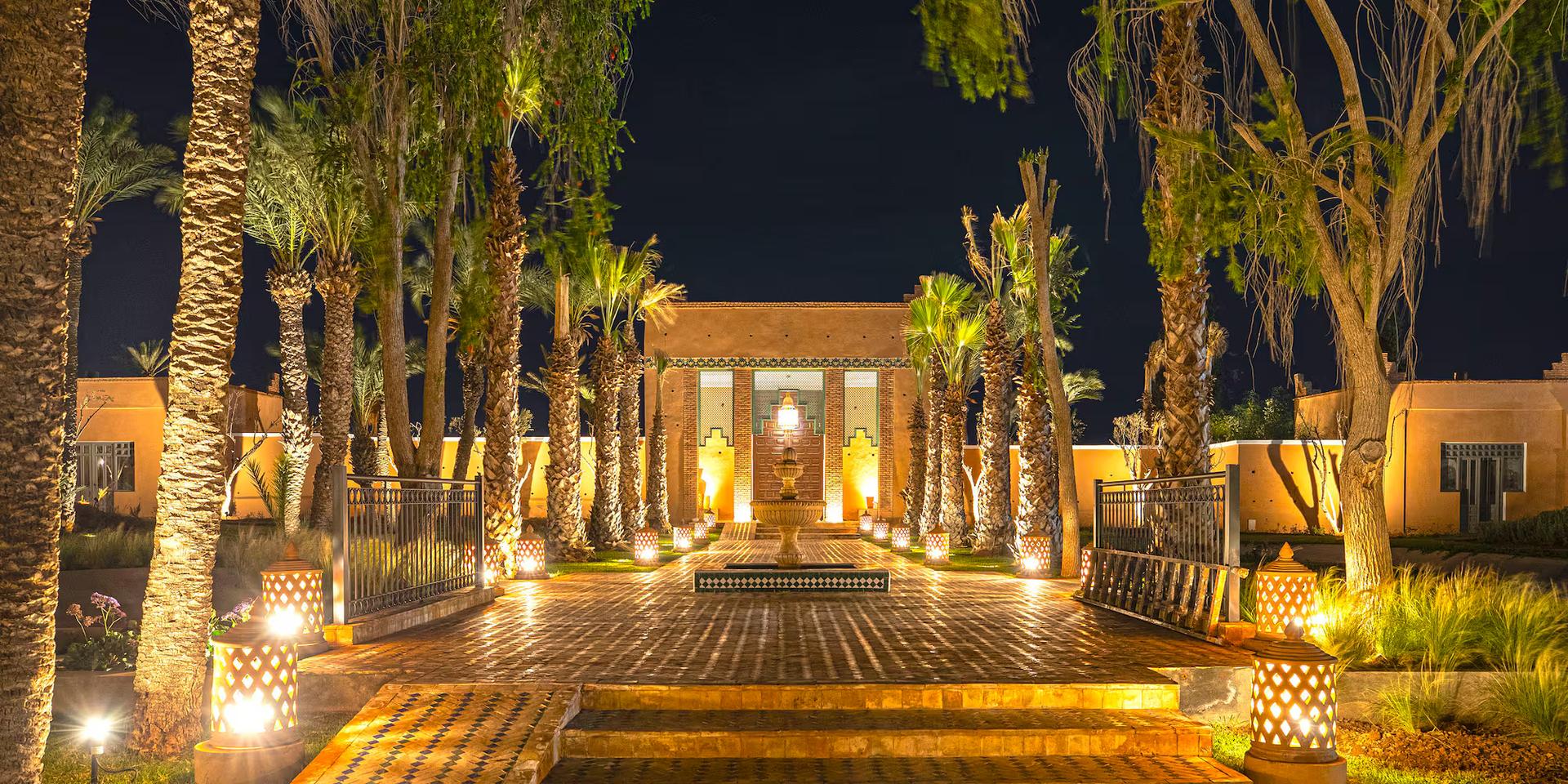 A well lit walkway lined with palm trees at Sol Oasis Marrakech by Melia