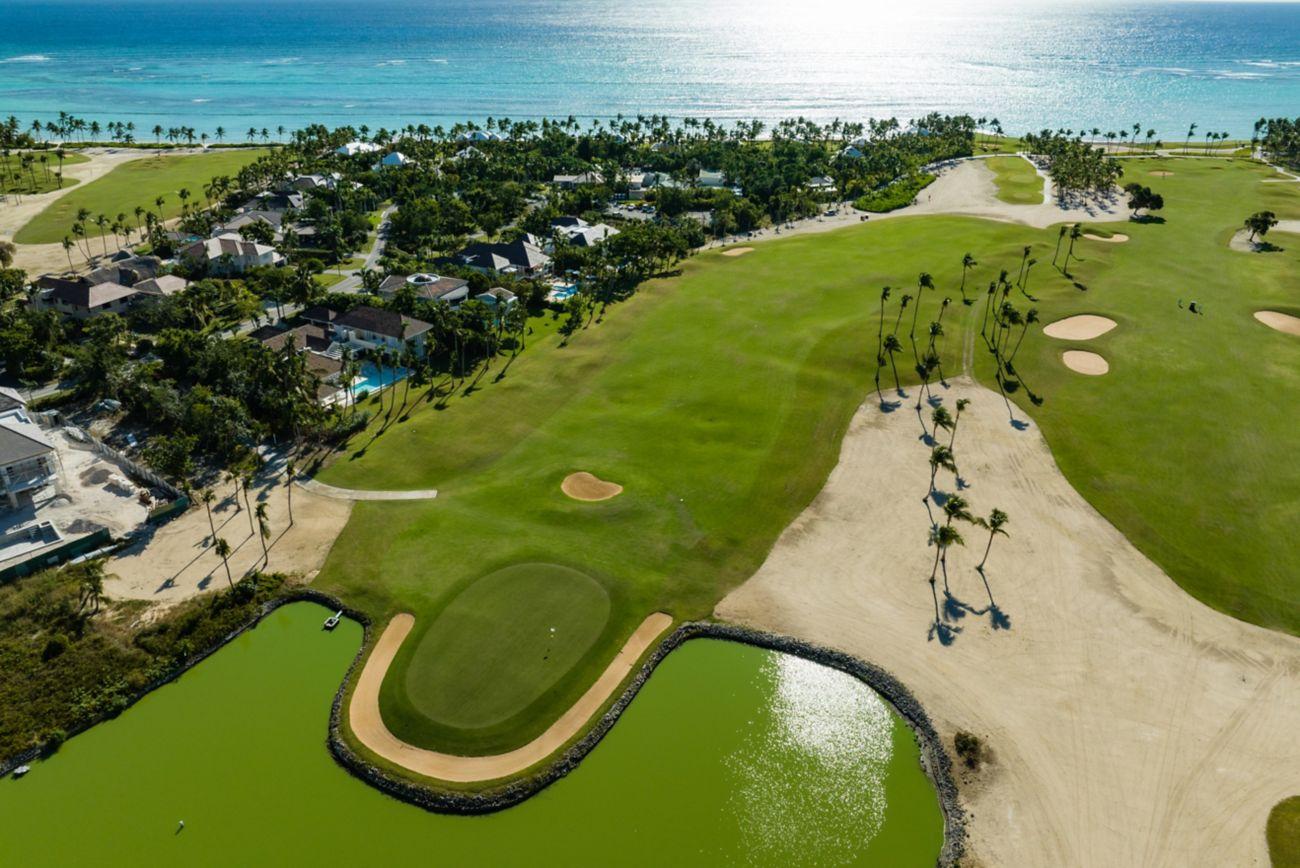 Overhead view of a well maintained fairway leading to a smooth green with a green water hazard
