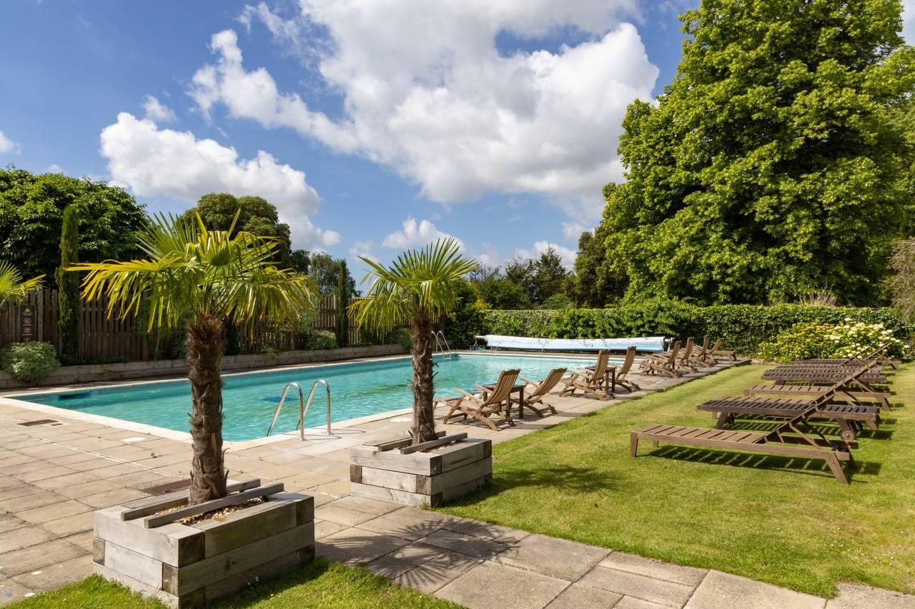 Outdoor swimming pool at Avisford Park Hotel lined with sunbeds at Avisford Park Hotel
