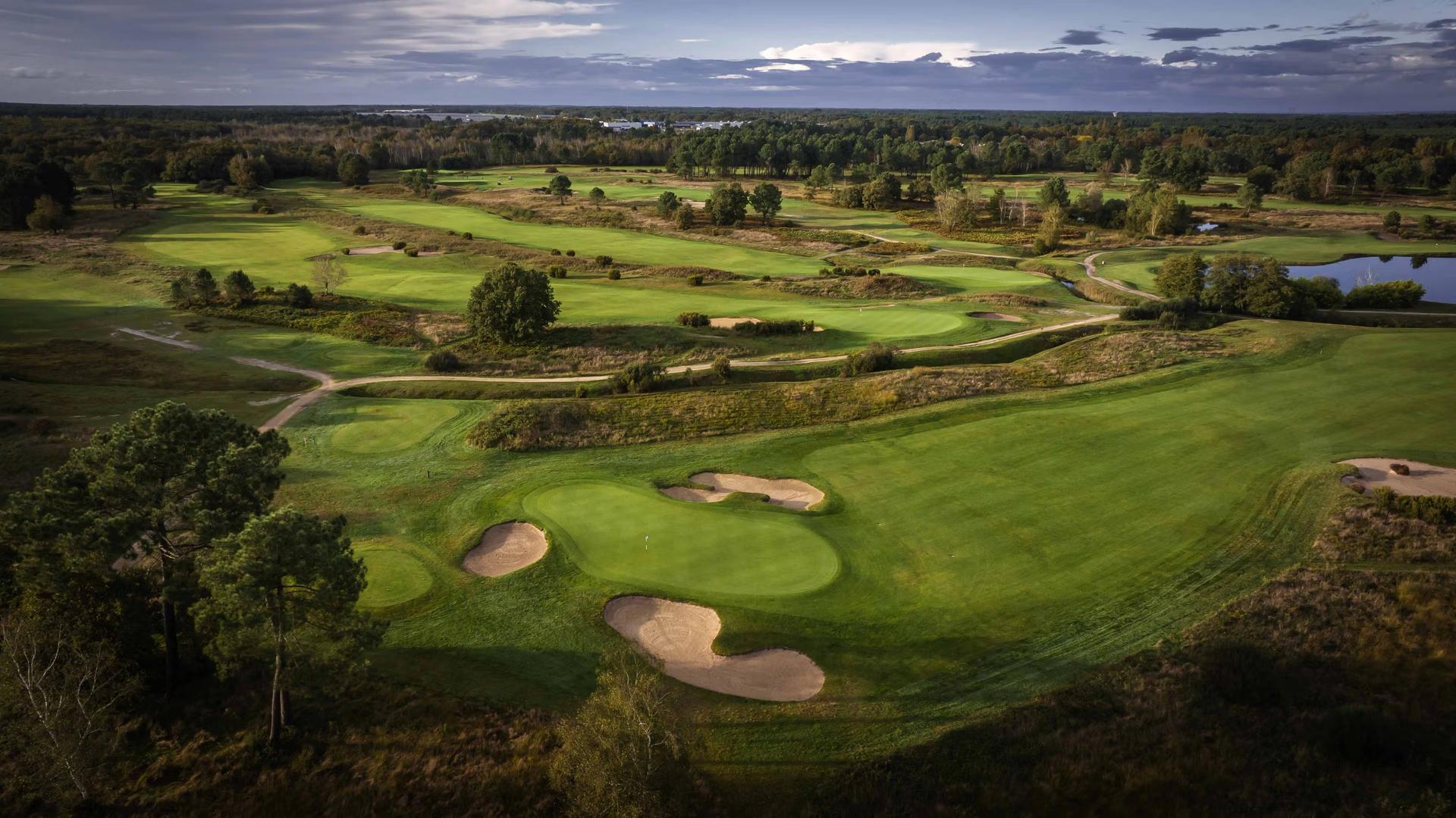 Overhead view of a well maintained fairway leading to a smooth green surrounded by sand bunkers