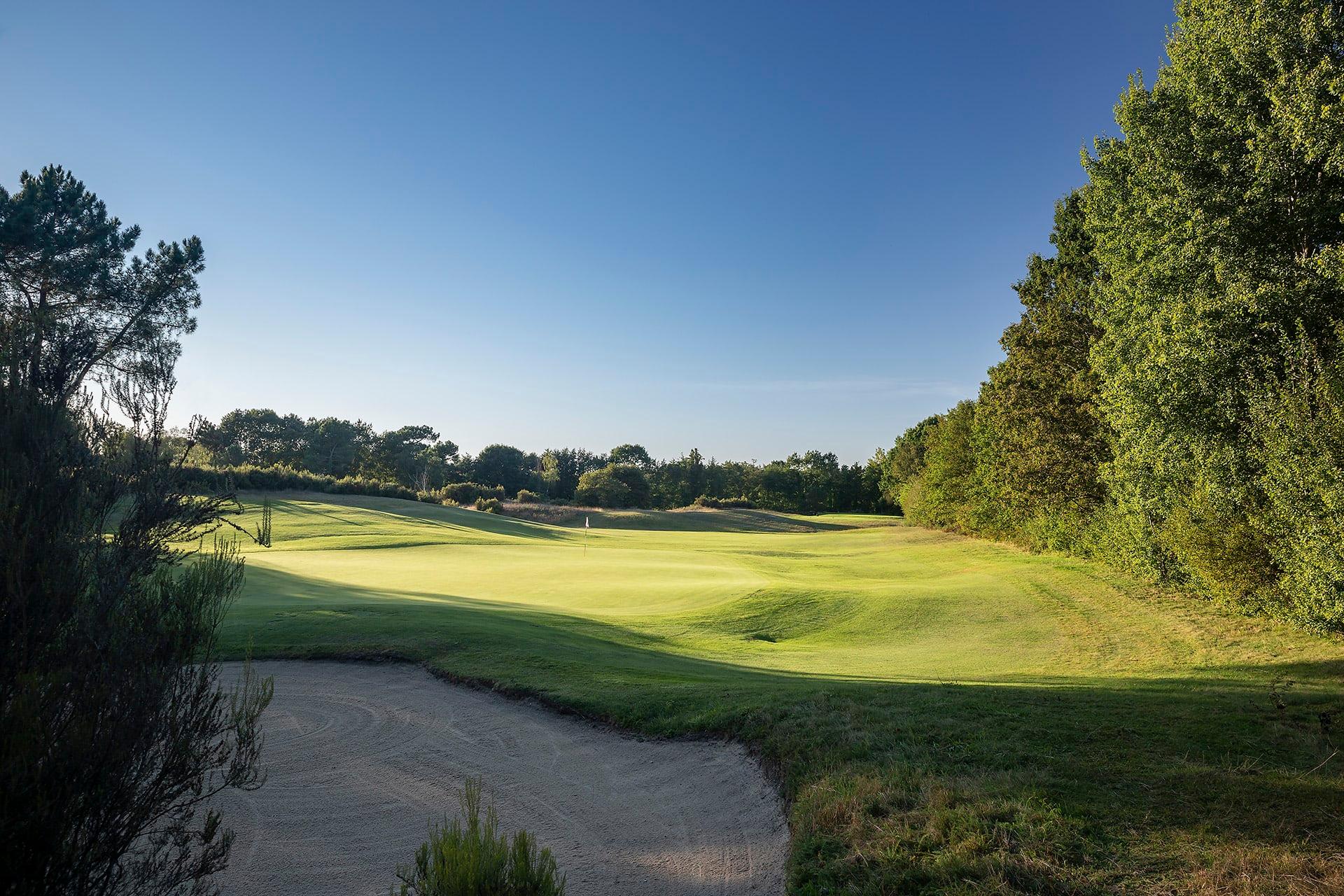 A smooth green next to a large sand bunker