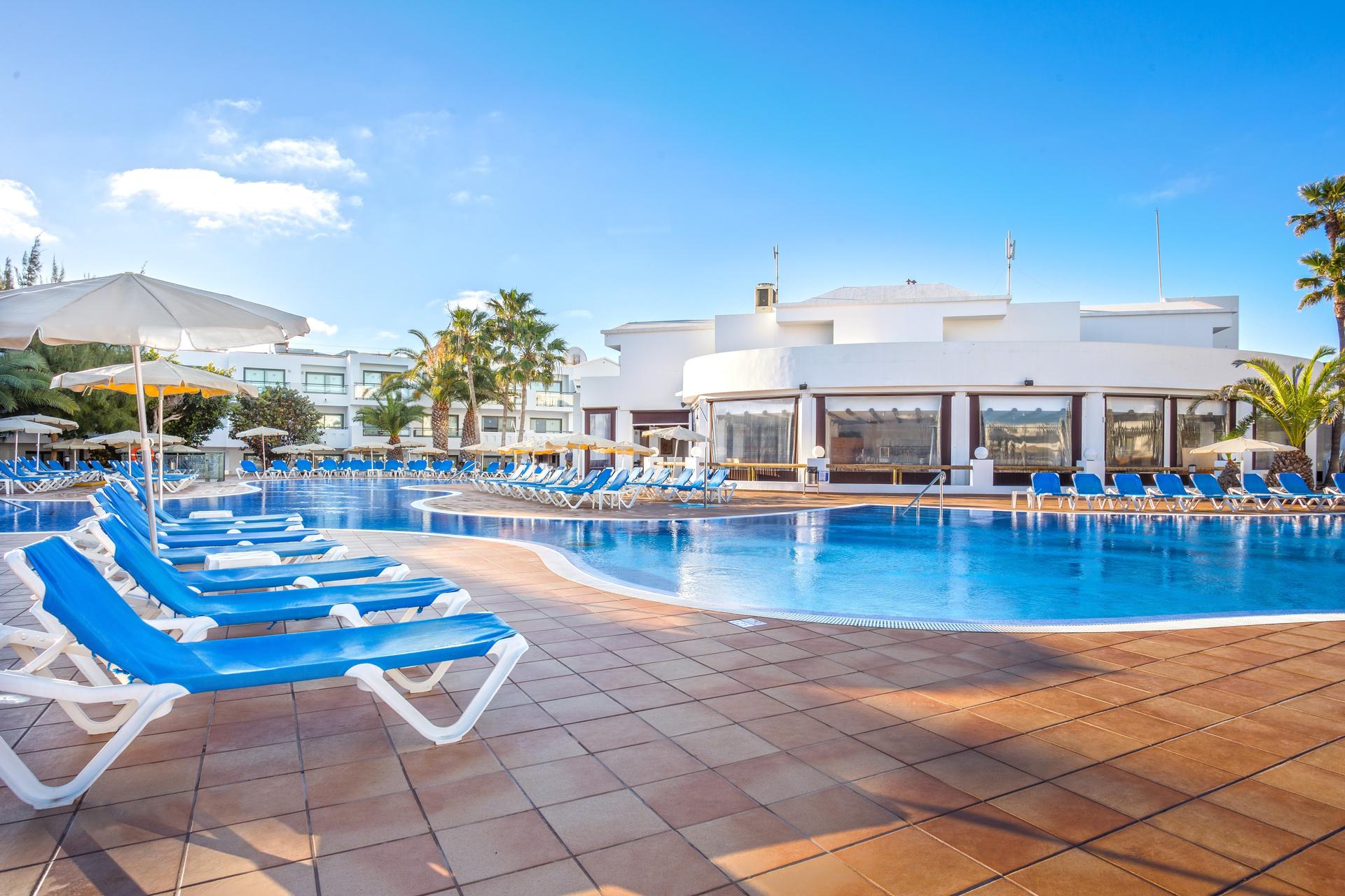Outdoor swimming pool lined with sun beds at THB Lanzarote Beach