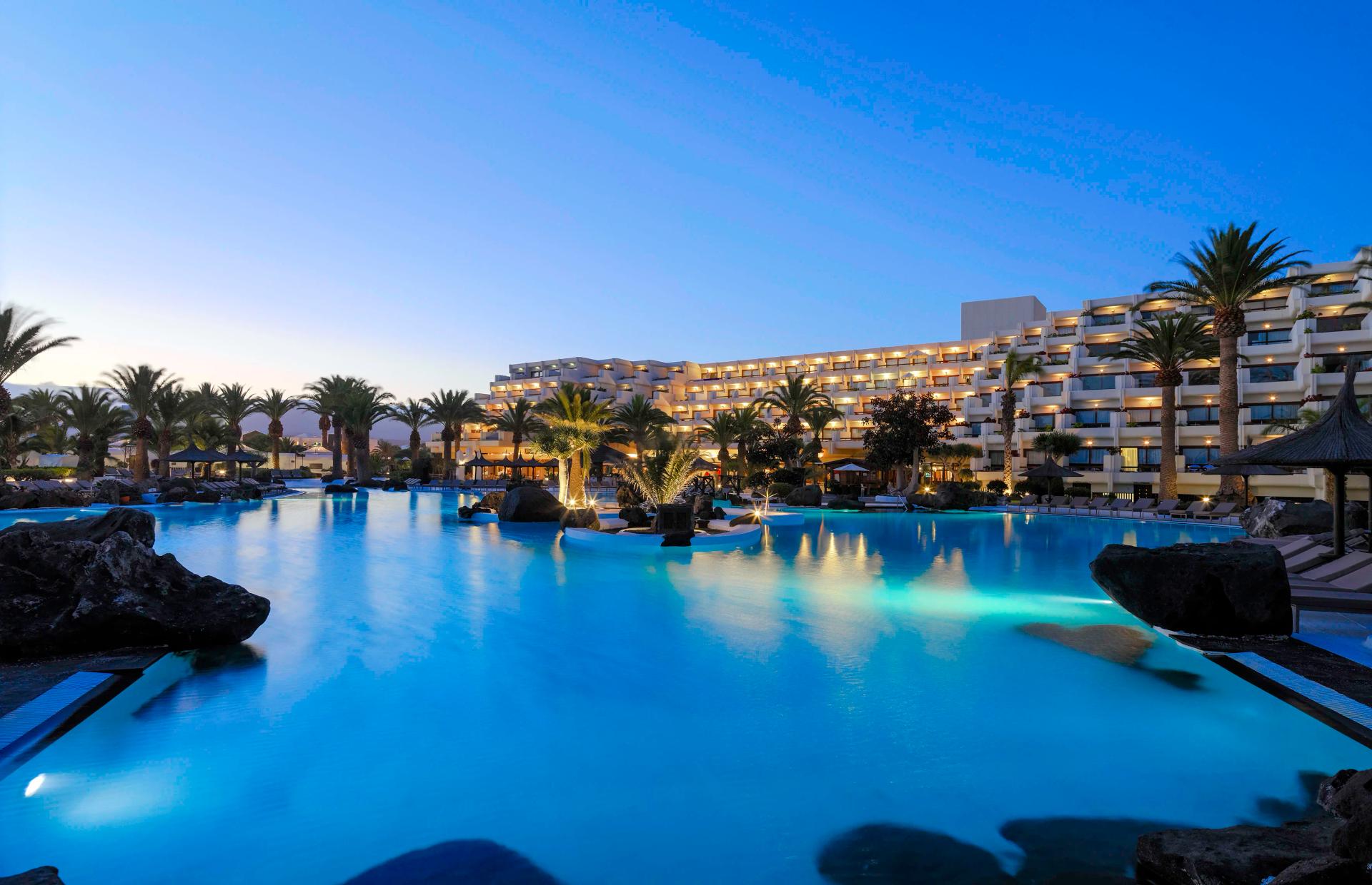 Panoramic view of the Paradisus Salinas Lanzarote building overlooking the outdoor pool lit up at evening