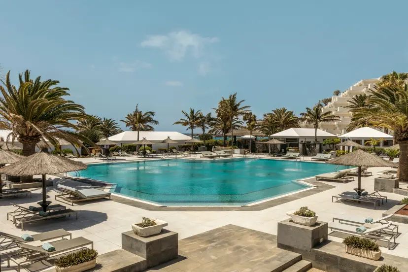 Outdoor swimming pool lined with sunbeds at Paradisus Salinas Lanzarote
