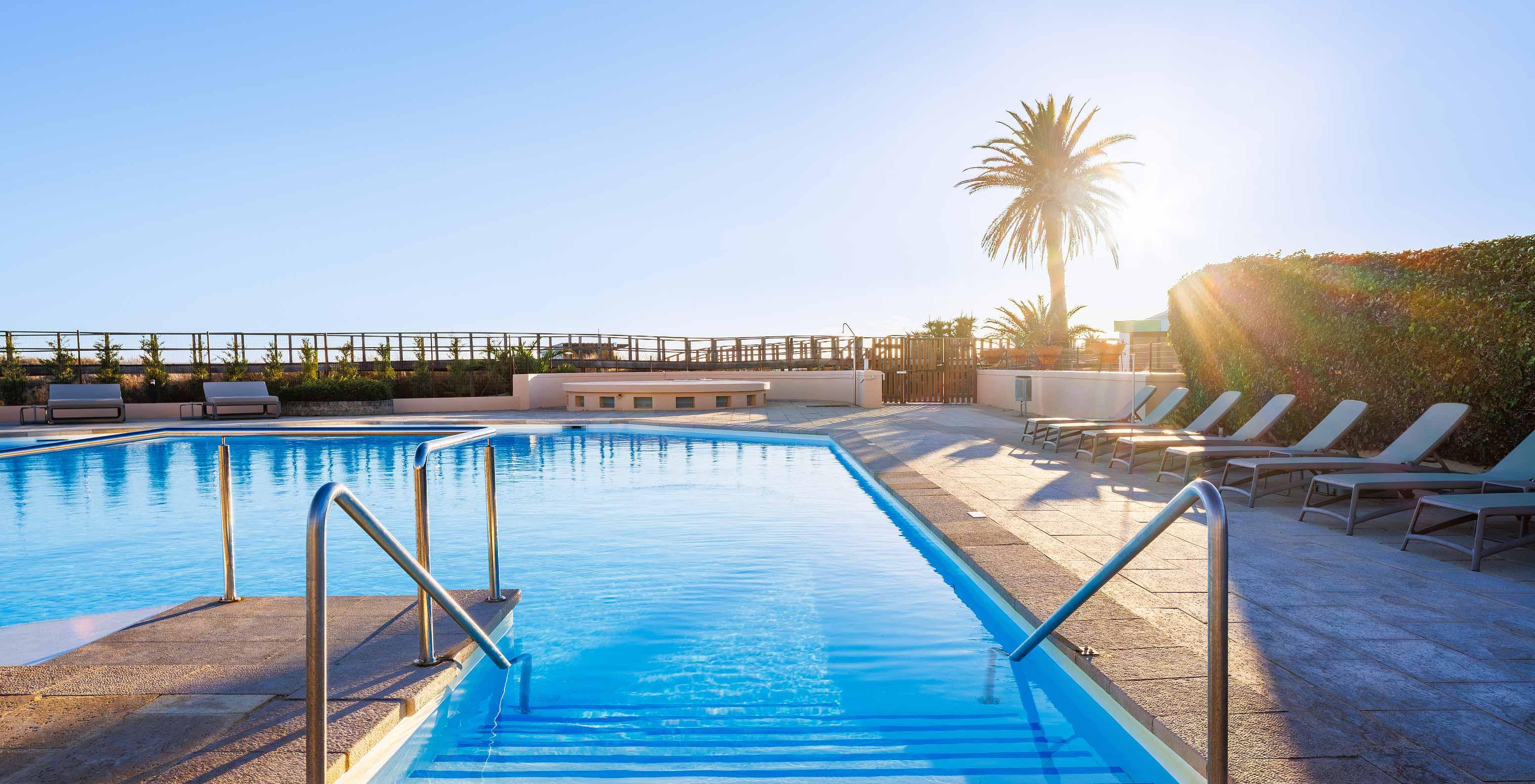 Sun shining over the outdoor swimming pol at Pestana Alvor Beach Villas