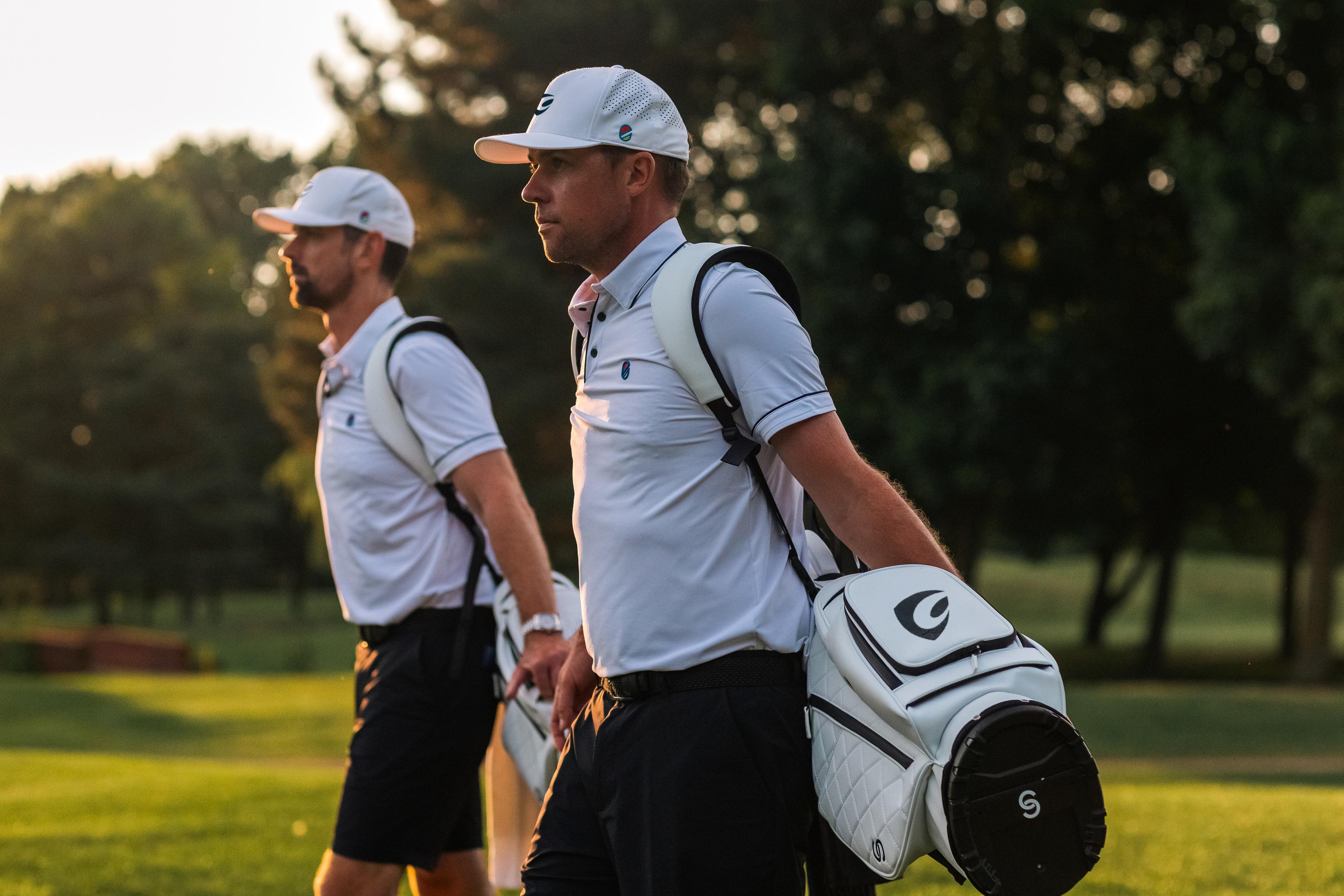 Golfers with their golf bags with the sunset in the background.