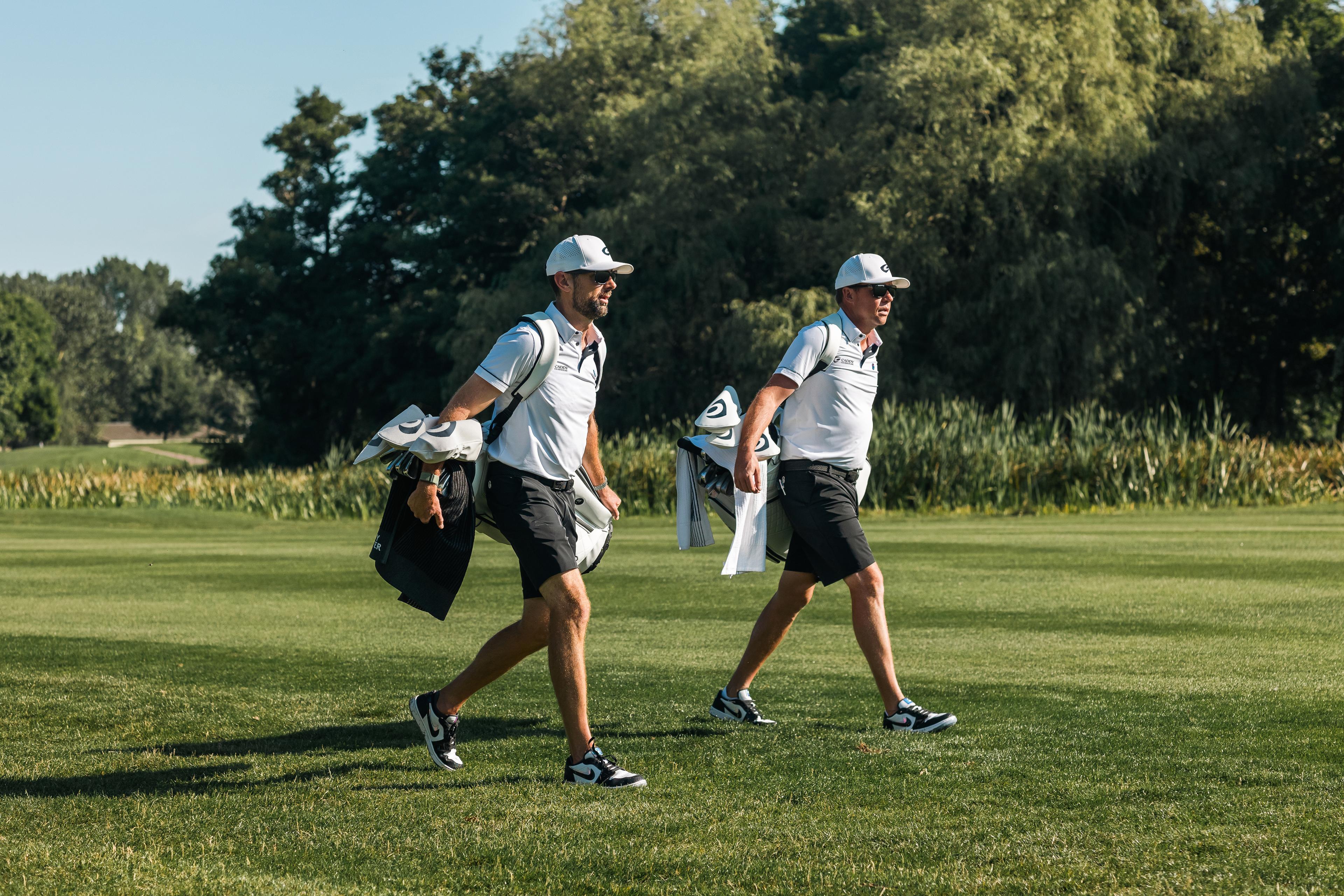 Golfers walking on the fairway with their golf bags.